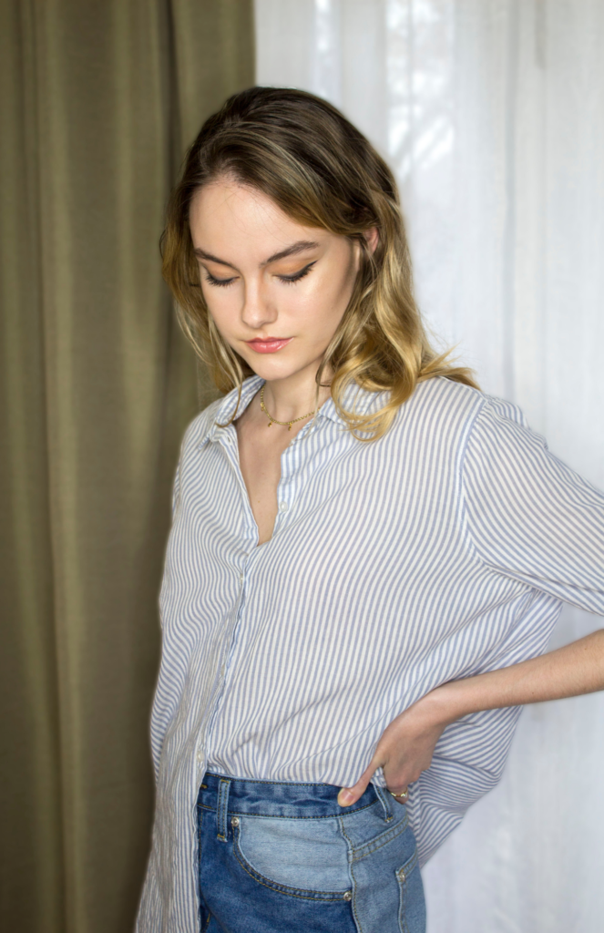 Effortlessly chic: Half-tucked light blue and white fine-striped flowy dress shirt with rolled-up sleeves, adding a touch of flair to this put-together look.