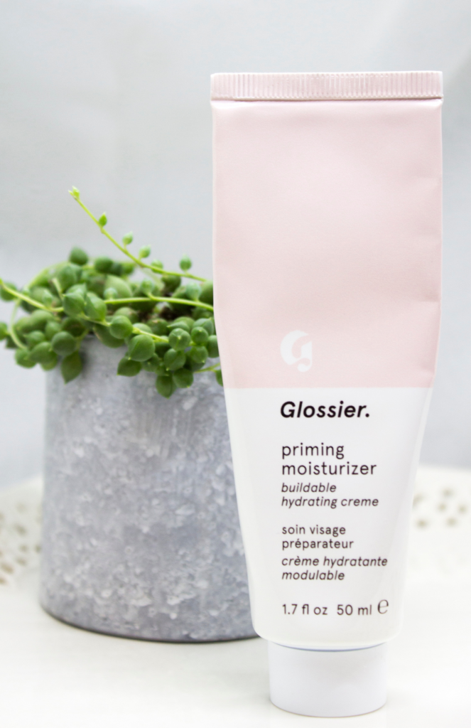 Packaging of Glossier's Priming Moisturizer beautifully displayed. This cult-favorite product is designed to hydrate and prime the skin, creating a smooth canvas for makeup application.