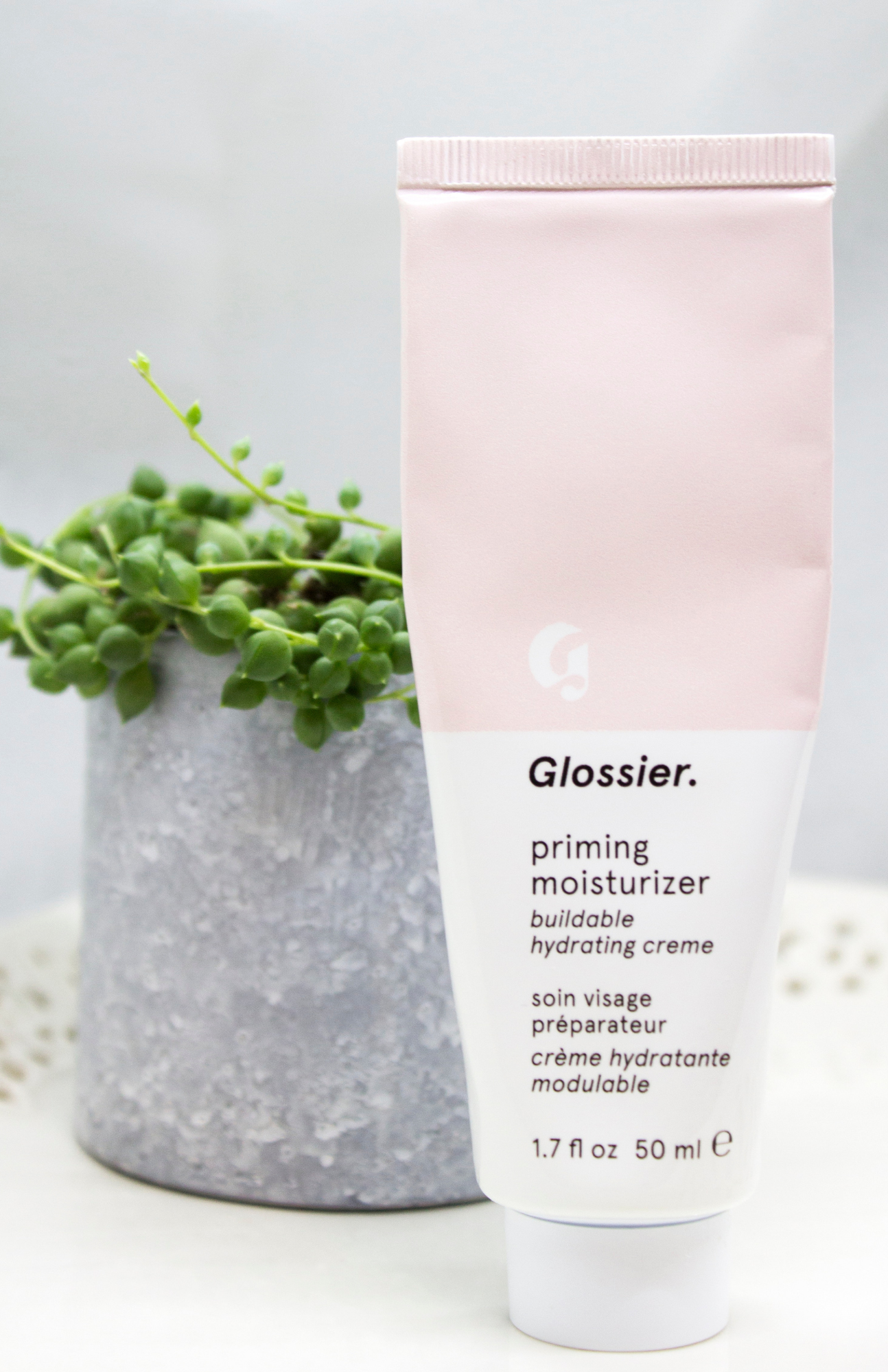 Glossier Priming Moisturizer in its beautifully designed packaging, promoting radiant skin.