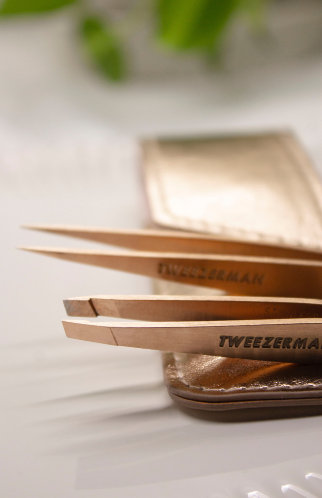 A beautiful close-up image of Tweezerman's Rose Gold Petite Tweezers