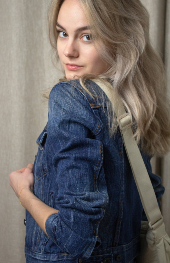 Stylish content creator wearing a denim jacket and jeans paired with a blue undershirt. Completing the look with a chic round mini crossbody bag in natural color from UNIQLO.