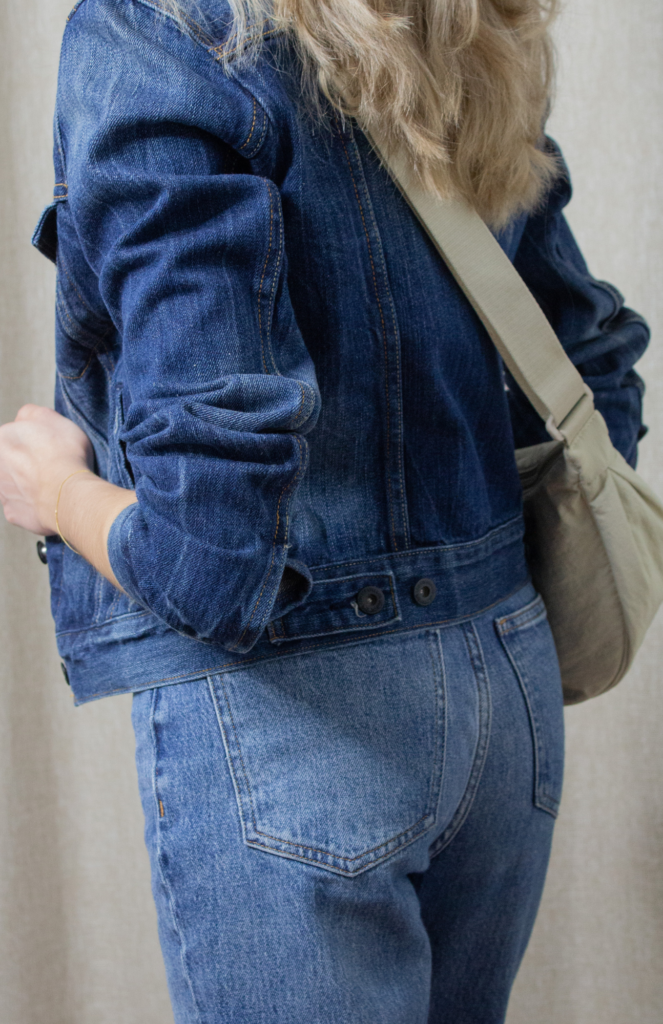 Stylish content creator wearing a denim jacket and jeans paired with a blue undershirt. Completing the look with a chic round mini crossbody bag in natural color from UNIQLO.