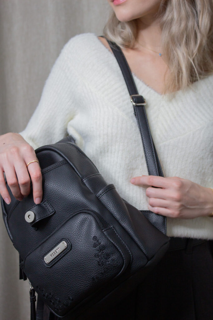 Fashion influencer exuding sophistication in an ivory v-neck sweater from H&M Divided, elegantly combined with UNIQLO's Brushed Jersey Pleated Wide Pants in a rich dark brown, complemented by a close-up shot featuring the Rosetti small backpack. It's a quiet luxury!