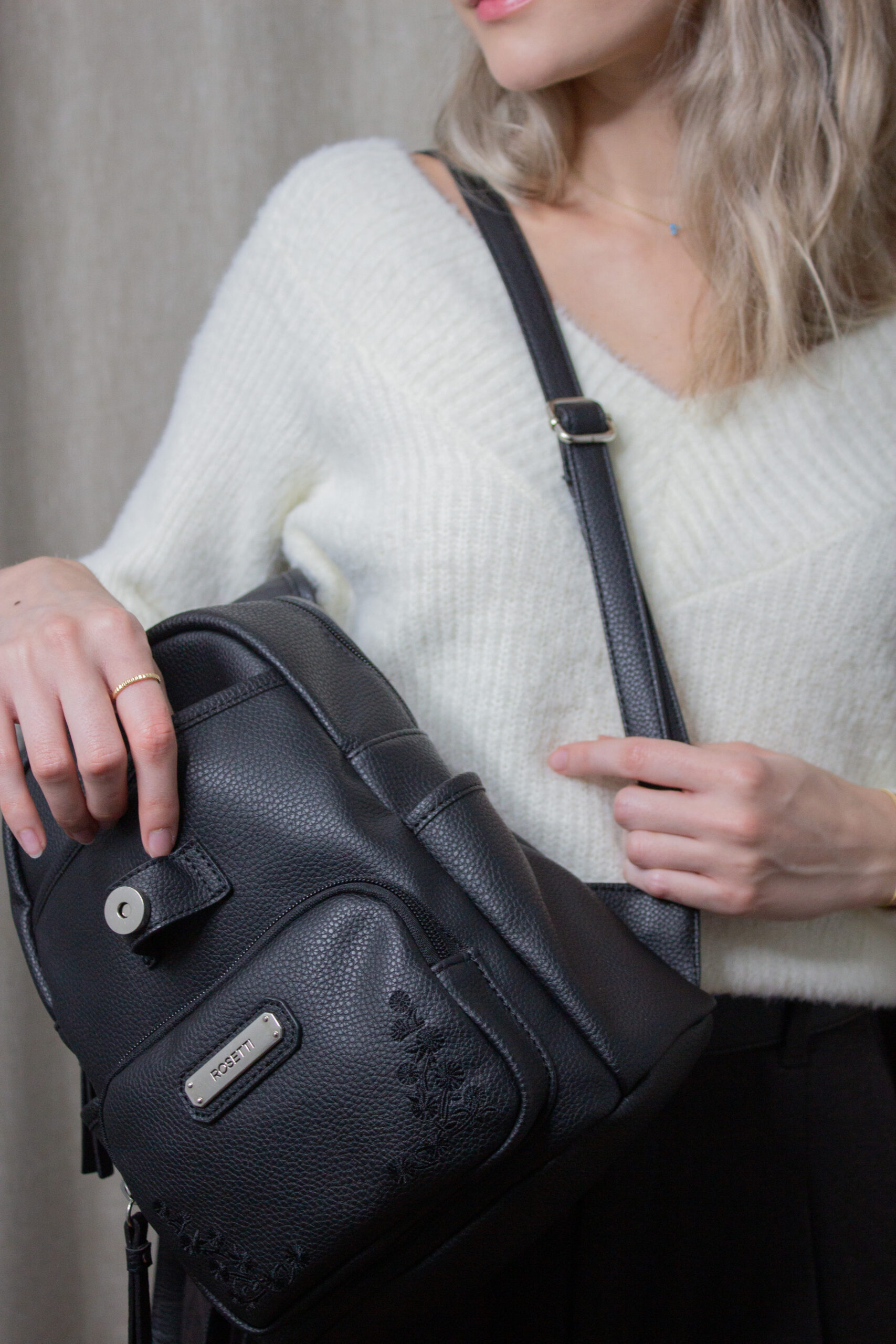 Fashion influencer exuding sophistication in an ivory v-neck sweater from H&M Divided, elegantly combined with UNIQLO's Brushed Jersey Pleated Wide Pants in a rich dark brown, complemented by a close-up shot featuring the Rosetti small backpack.