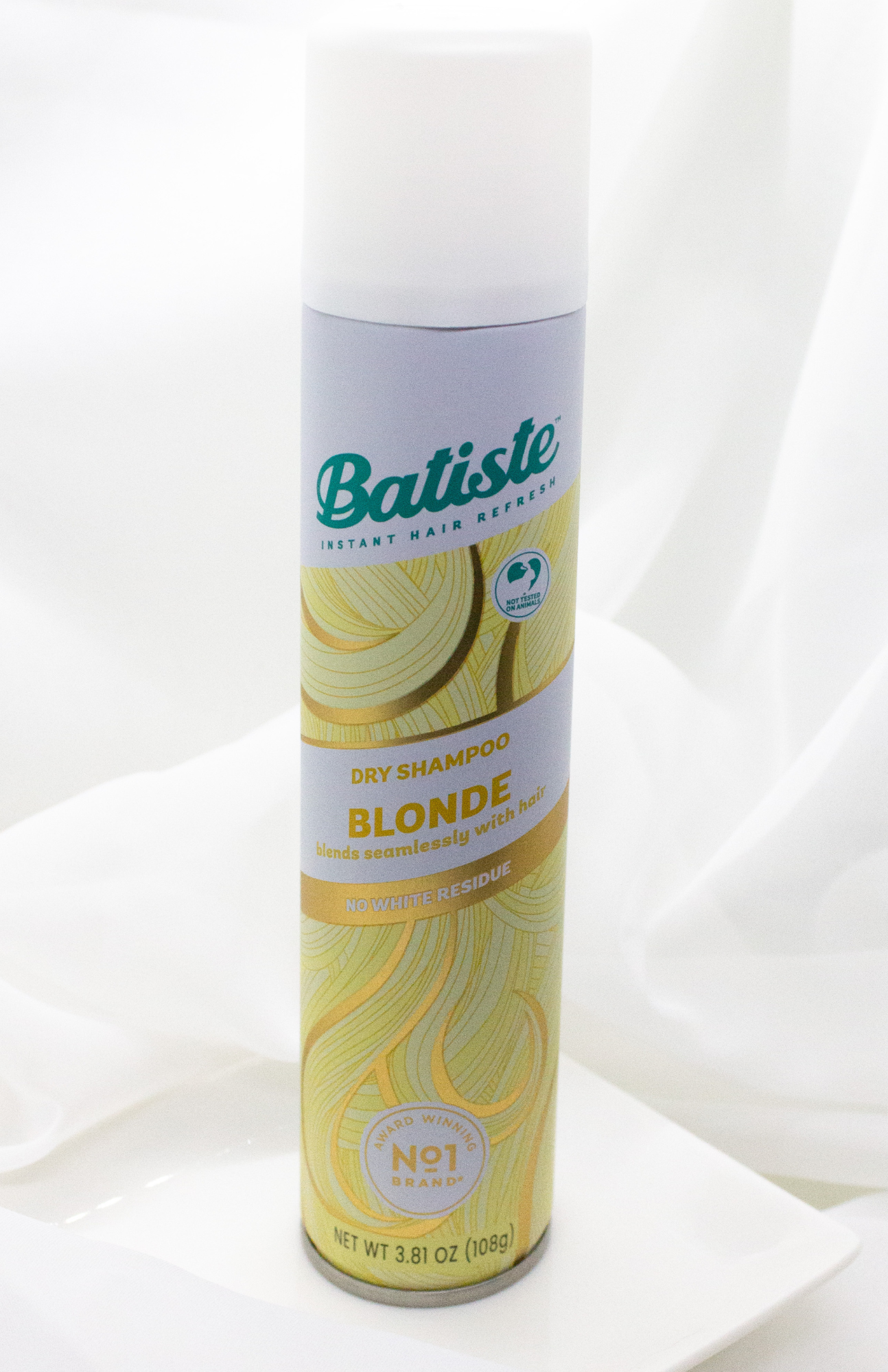 A sleek Batiste Blonde Dry Shampoo can, highlighted against a light backdrop, showcasing its vibrant design and promise of instant freshness for blonde hair.