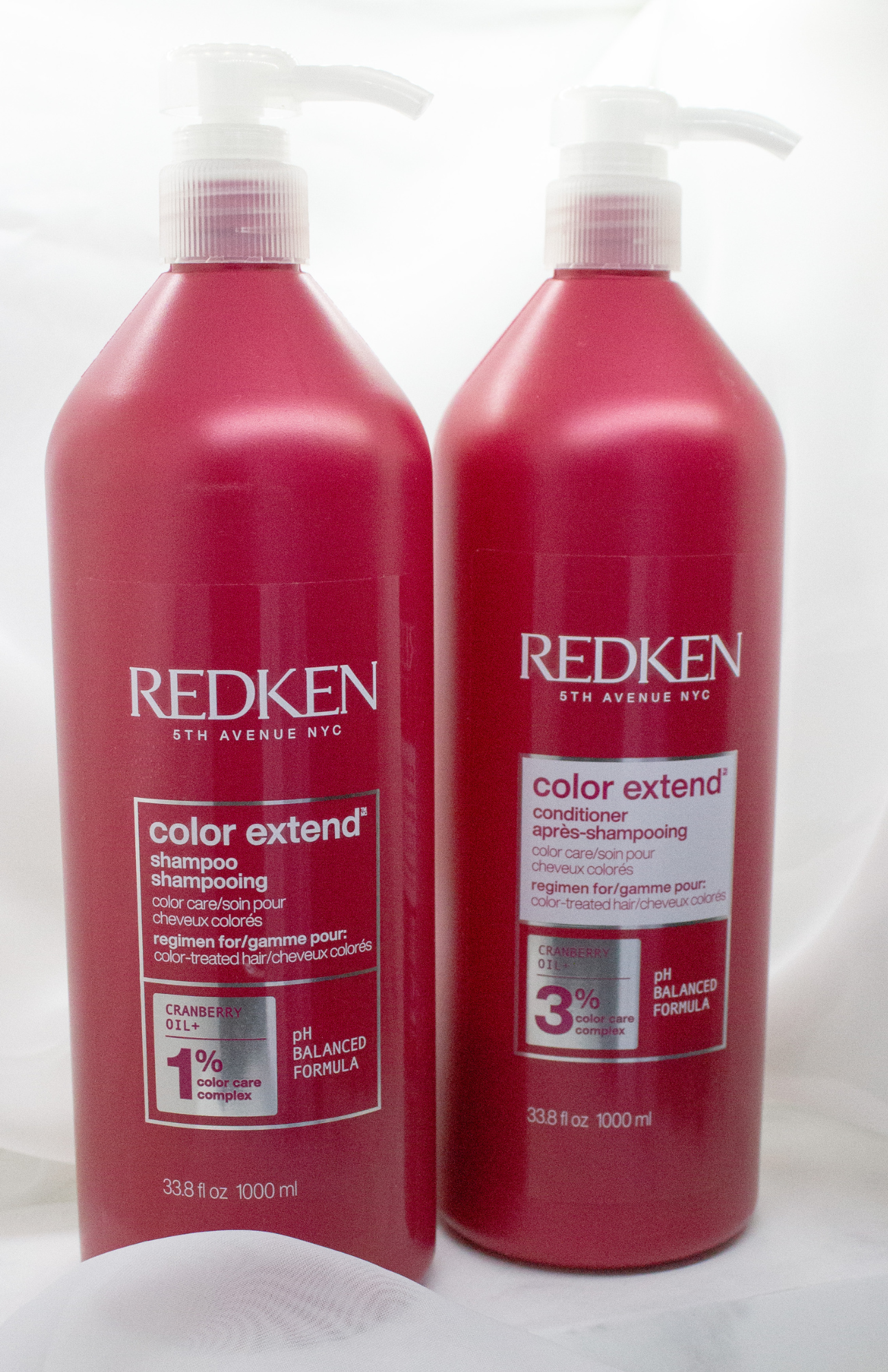 The REDKEN Color Extend Shampoo & Conditioner set elegantly showcased against a soft cloud veil backdrop, highlighting the sleek design of the packaging and the vibrant colors of the tubes.