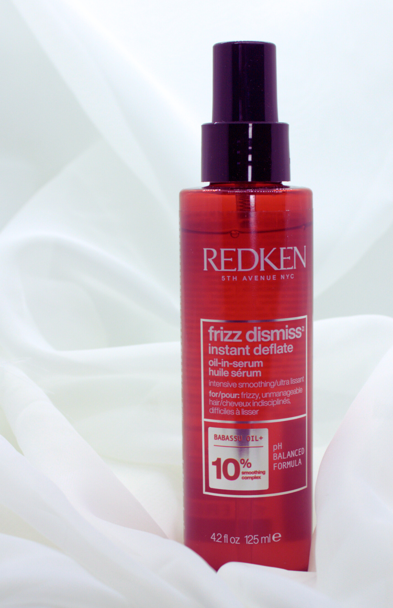 Redken Frizz Dismiss Instant Deflate Oil-in-Serum bottle for frizz control and smoothing dry, puffy ends on color-treated hair.