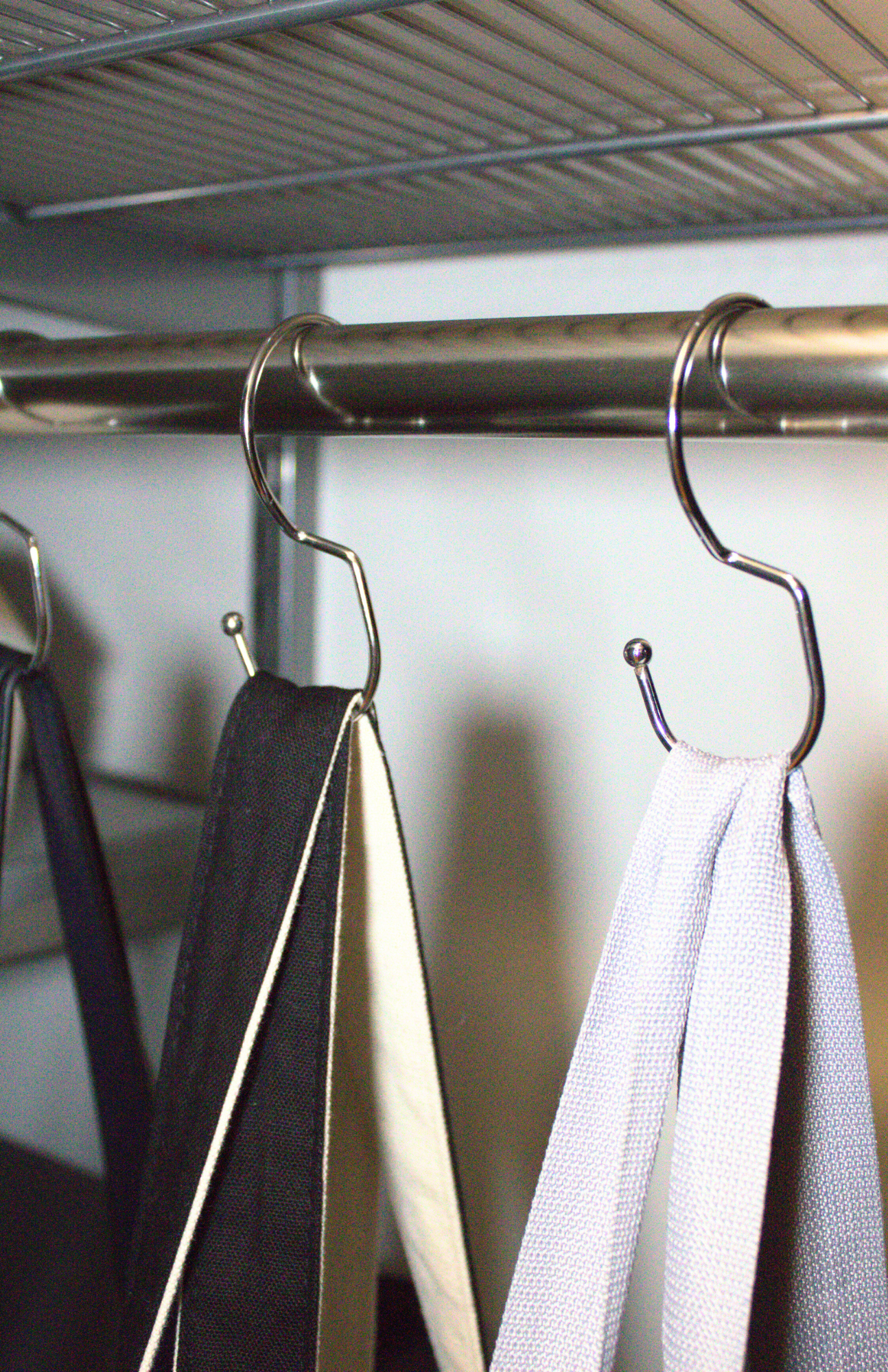 Organization ideas, handbags neatly hung on metal purse hangers inside a closet to maximize vertical space.