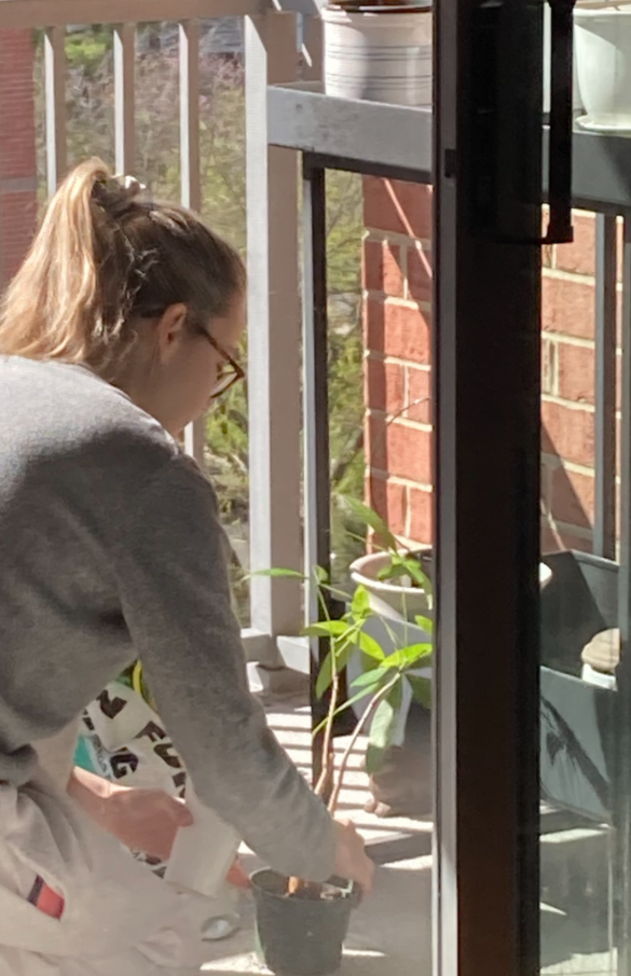 Spring reset inspiration featuring the content creator tending to potted plants on a sunny apartment balcony with natural light filling the space.